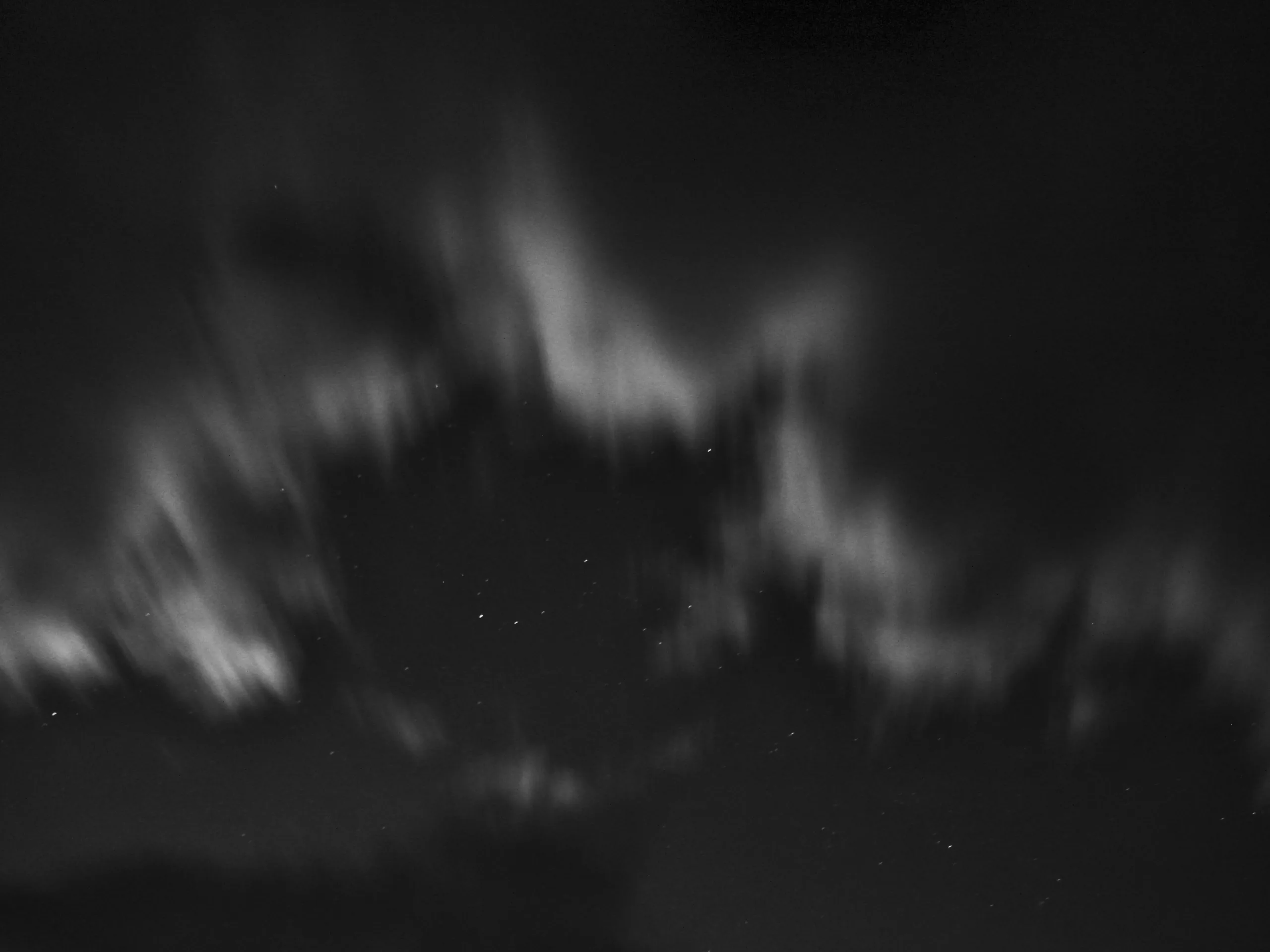 Rushing clouds blow past the dark starry night sky